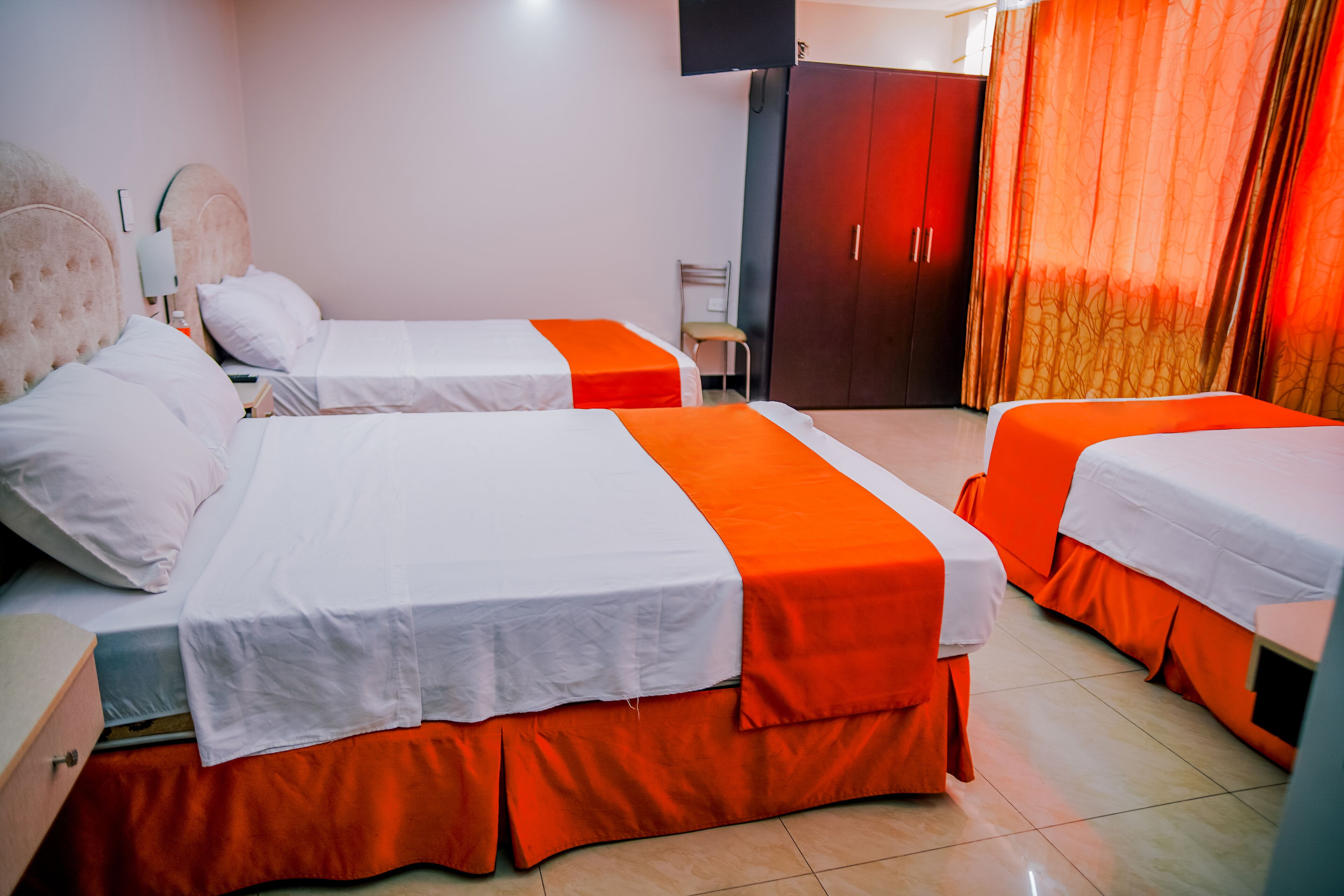 Habitación de hotel con dos camas, un armario, un televisor y una silla.