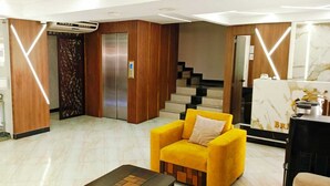A modern lobby with a reception desk, a yellow armchair, a staircase, and an elevator. - BRITNEY HOTEL MACHALA (Machala)
