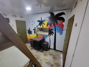 A room with a bunk bed, a small table, and a mural with palm trees and birds. - Ocean View  (Riohacha)