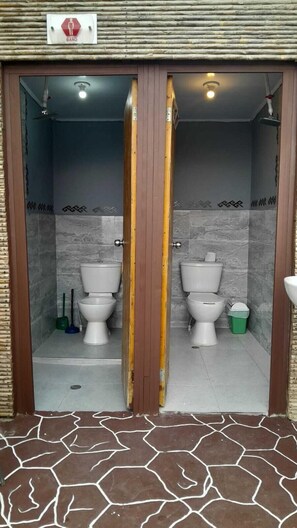 Herretoilet med to toiletter, en trädør og flisegulv.
