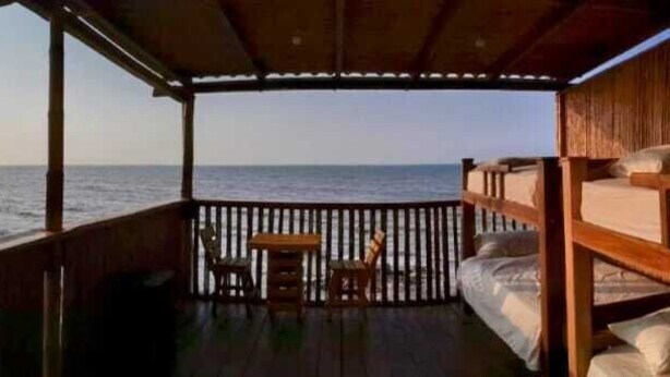 A wooden deck with a bed and a table, overlooking the sea. - Ocean View (Riohacha)