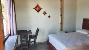 A room with a bed, a desk, and a chair. There are decorative wall hangings and a bamboo pillar. - Ocean View (Riohacha)