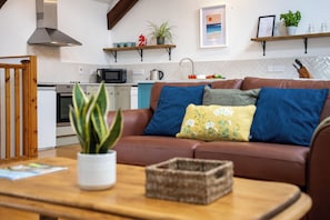 A modern living room with a brown sofa, a wooden coffee table, and a kitchen in the background.