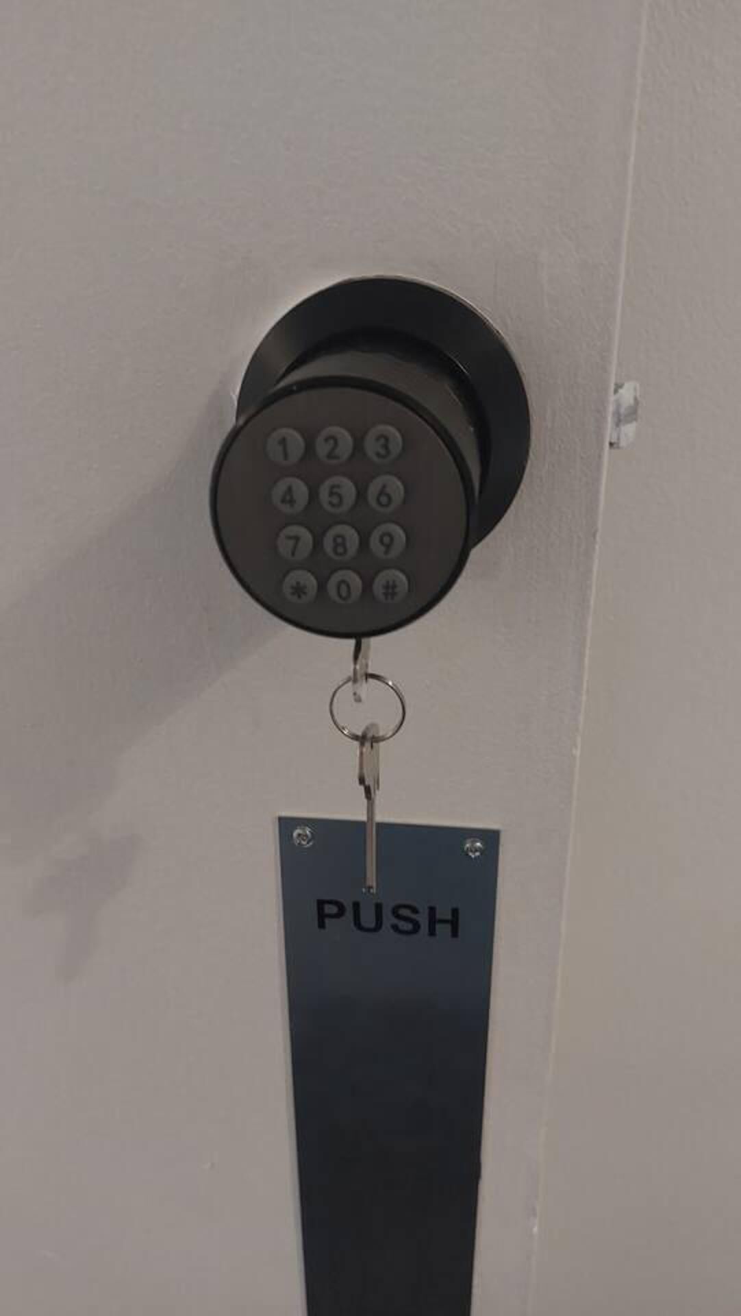 A push-button telephone keypad attached to a door with a push sign below it.