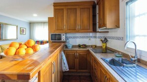 Cozinha com armários de madeira, micro-ondas e pia.