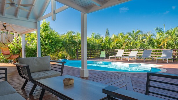 Área externa coberta com piscina, espreguiçadeiras e deck de madeira.