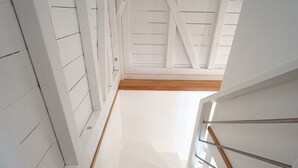 Escada com paredes brancas e piso de madeira que dá acesso a um andar superior.