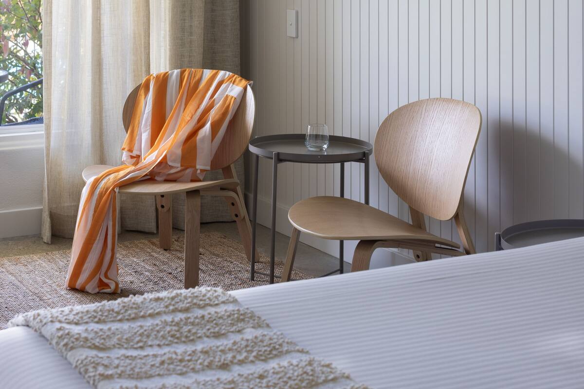 Una habitación de hotel con cama, dos sillas, una mesita y una ventana con cortinas.
