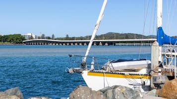Un velero amarrado cerca de un muelle, con un puente al fondo.