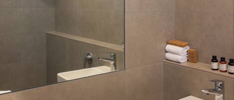 A modern bathroom with a large mirror, a white sink, and a shower.