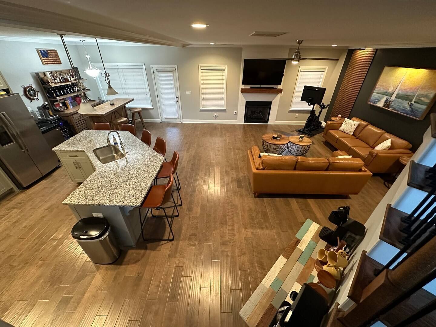 Eine moderne Küche mit Granit Arbeitsplatte, ein Essbereich mit orangefarbenen Stühlen, ein Wohnzimmer mit braunem Ledersofa und ein Kamin.