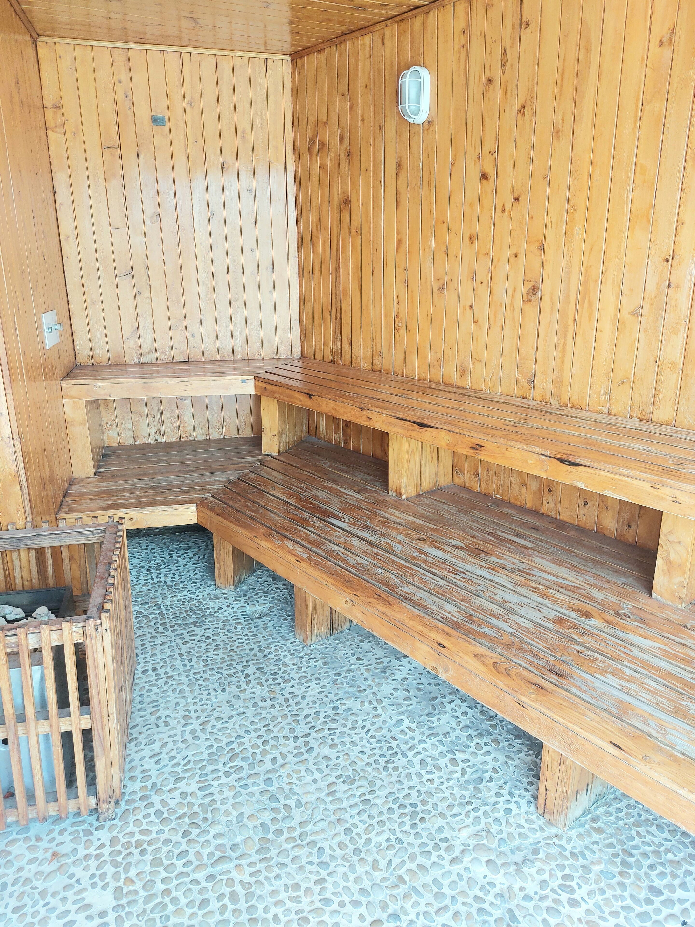 Un sauna en bois avec des bancs et une petite fenêtre.