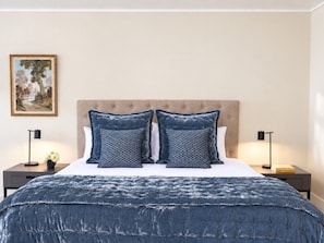 A bedroom with a bed, two nightstands, a lamp, and a painting on the wall.