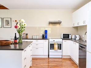 A modern kitchen with white cabinetry, a built-in oven, a microwave, and a coffee maker.