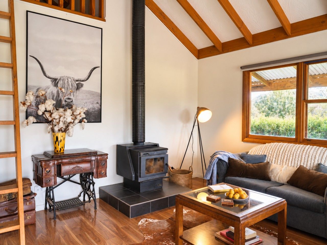 A cozy living room with a wood-burning stove, a sofa, a coffee table, and a painting of a bull.