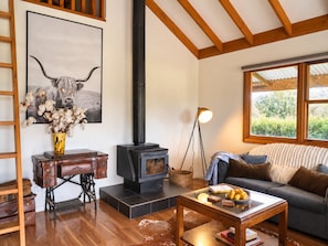 A cozy living room with a wood-burning stove, a sofa, a coffee table, and a painting of a bull.