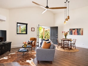 A spacious living room with a ceiling fan, a fireplace, and a dining area with a round table and chairs.