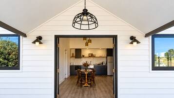 A modern kitchen with a dining area, white exterior walls, and a concrete floor.
