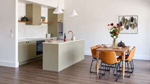 Eine moderne Küche mit Kochinsel, Holzboden und Pendelleuchten.