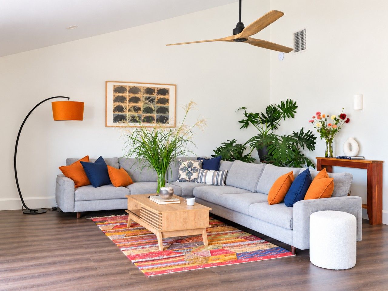 A modern living room with a grey sofa, a wooden coffee table, and a colorful rug.
