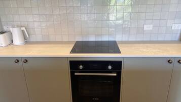 Una cocina con horno Bosch, salpicadero de azulejos blancos y armarios de colores claros.