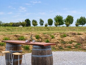 A rustic outdoor seating area with a wooden table and stools, set against a backdrop of a grassy field and trees. - Shawwood Winery Luxury Mudgee Farm Stay,  close to town and wineries (Bombira)