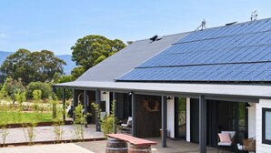 Ein modernes Haus mit Solardach, überdachter Außenbereich und Garten.