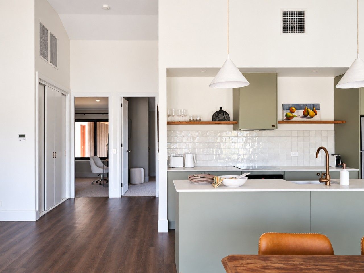A modern kitchen with a central island, pendant lighting, and a view into the dining area.