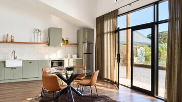 A modern kitchen with a dining area, large windows, and a view of the outdoors.