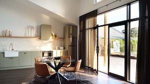 A modern kitchen with a dining area, large windows, and a view of the outdoors.