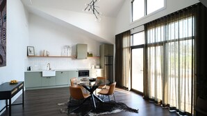 A modern kitchen with a dining area, large windows, and a chandelier.