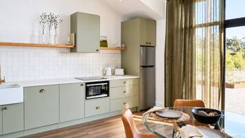 Une cuisine moderne avec un coin repas, comprenant une table en verre, un plancher en bois et une vue dégagée grâce à de grandes fenêtres.