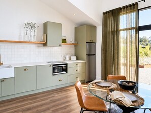 Una cucina moderna con zona pranzo, caratterizzata da un tavolo in vetro, pavimento in legno e vista panoramica attraverso ampie finestre.