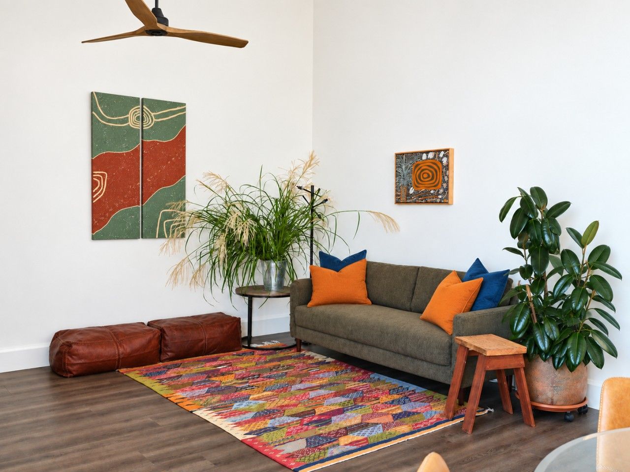 Een woonkamer met een bank, een salontafel, een vloerkleed en twee planten.