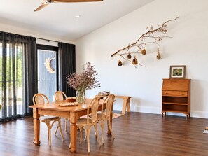 Ein Essbereich mit Holztisch und -stühlen, einer Blumenvase, einem Zweig mit hängenden Dekorationen und einem kleinen Holzschrank.