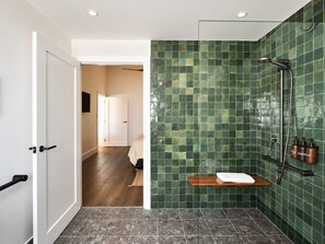 Un baño con ducha, un perchero para toallas y un estante de madera.