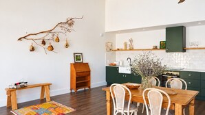 A modern kitchen with dark wooden flooring, a dining table with white chairs, and a ceiling fan. - Shawwood Barrel Room Luxury Mudgee Farm Stay, close to town and wineries (Bombira)