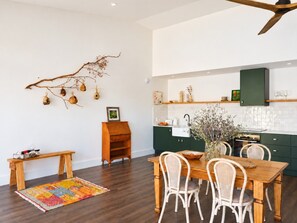 Una cocina moderna con piso de madera oscura, una mesa de comedor con sillas blancas y un ventilador de techo.