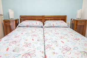 A double bed with floral bedding, wooden headboard, bedside tables, and a light blue wall.