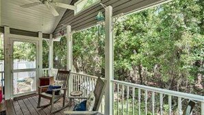 A covered porch with wooden railings and two rocking chairs. - 30A Private Pool Cottage with Pool and Golf Cart! (Santa Rosa Beach)