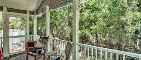 A covered porch with wooden railings and two rocking chairs.