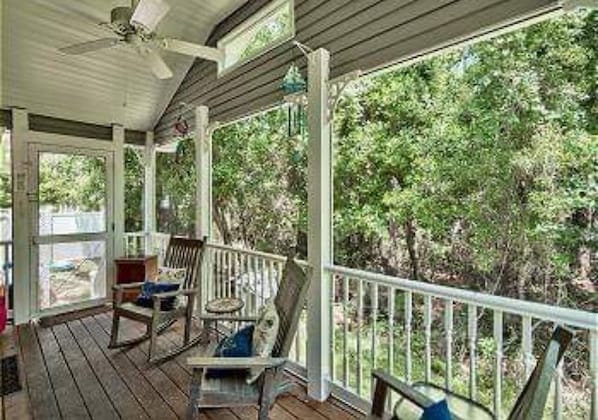 A covered porch with wooden railings and two rocking chairs. - 30A Private Pool Cottage with Pool and Golf Cart! (Santa Rosa Beach)