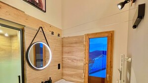 Une salle de bain moderne avec un plafond en bois, un grand miroir, un lavabo et une fenêtre donnant sur un beau paysage.