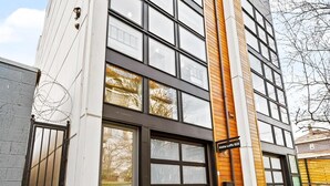 Moderni rakennus, jossa on suuret ikkunat, puusta tehty koristeellinen seinä ja kyltti, jossa lukee ”Alka Lofts 625”.
