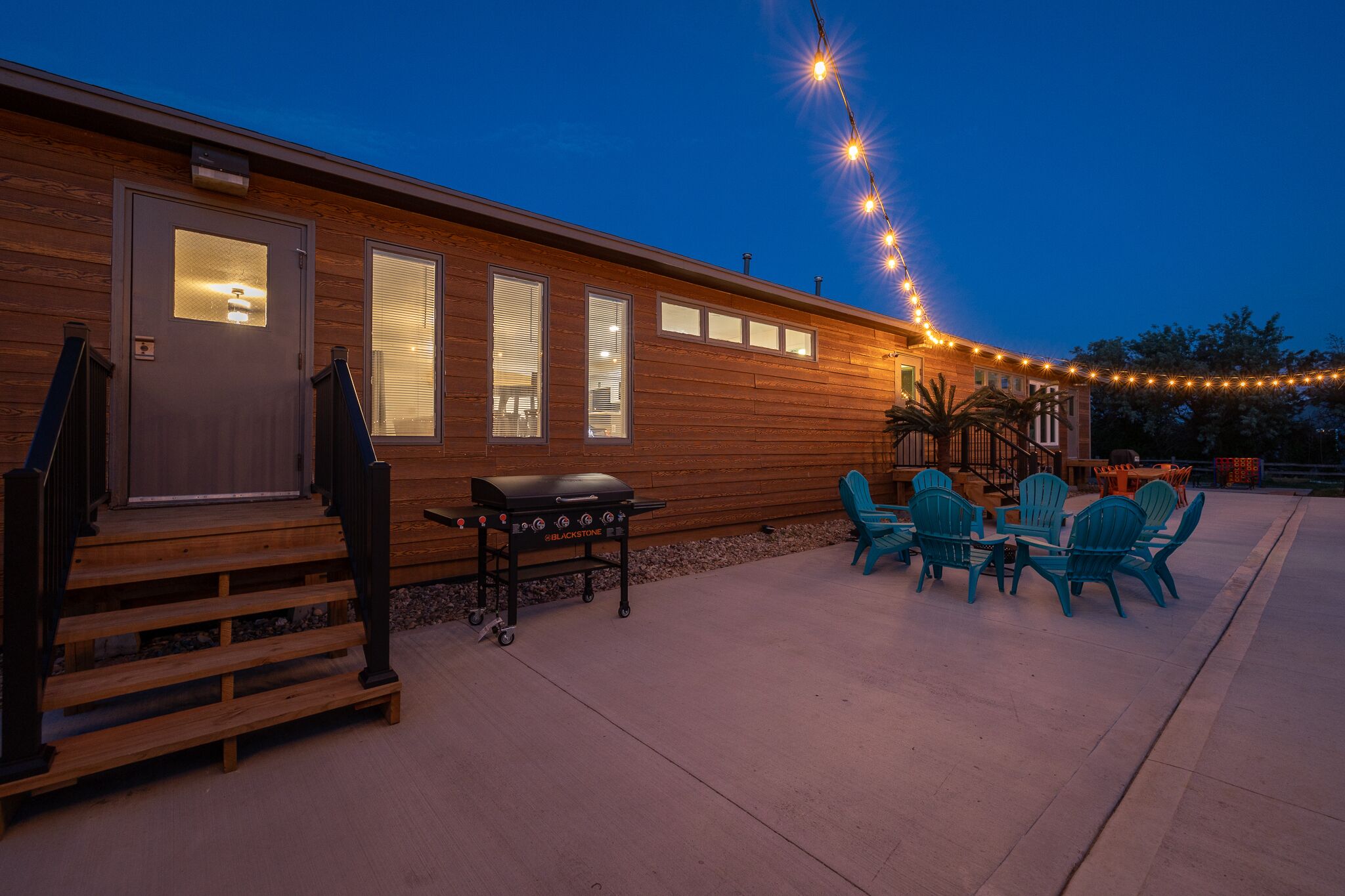 Un bâtiment en bois doté d’un patio couvert, de sièges en plein air et de guirlandes lumineuses.