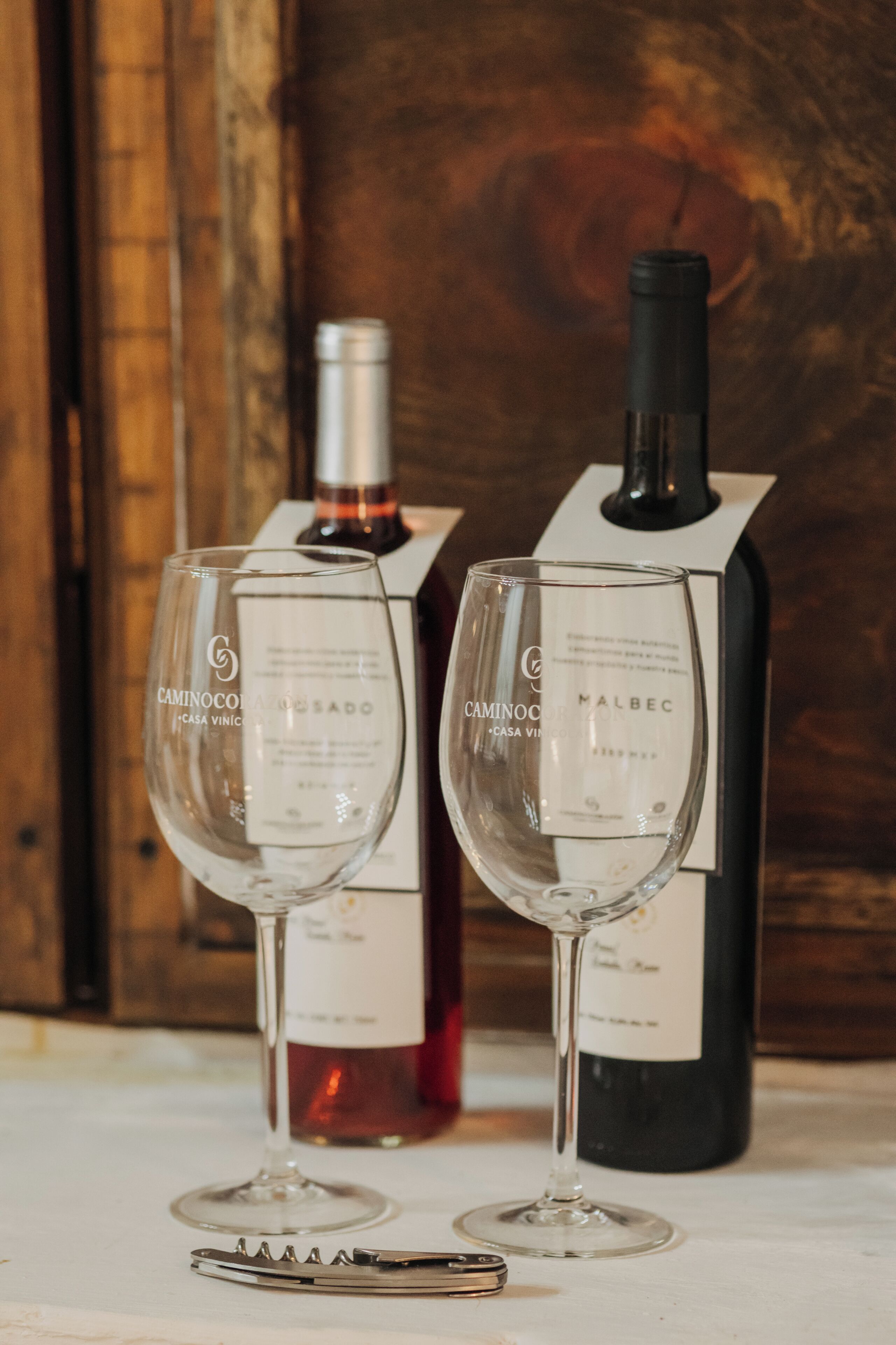 Two wine glasses and two wine bottles on a table.