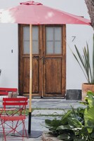 Una puerta doble de madera con el número 7, un paraguas rojo y una silla roja en el exterior.