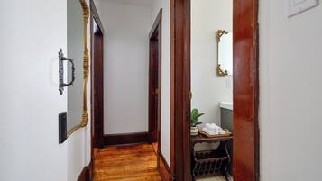 Un pasillo estrecho con piso de madera y una puerta que da a un baño.