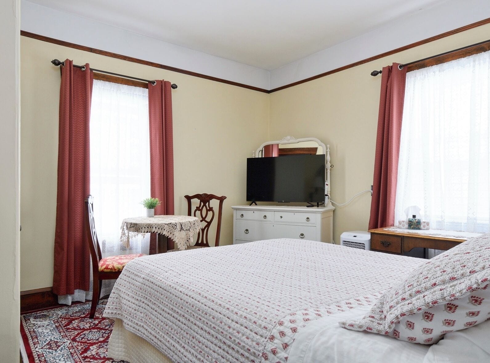 Un dormitorio con cama, televisión, cómoda y silla.