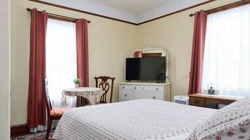 Un dormitorio con cama, televisión, cómoda y silla.